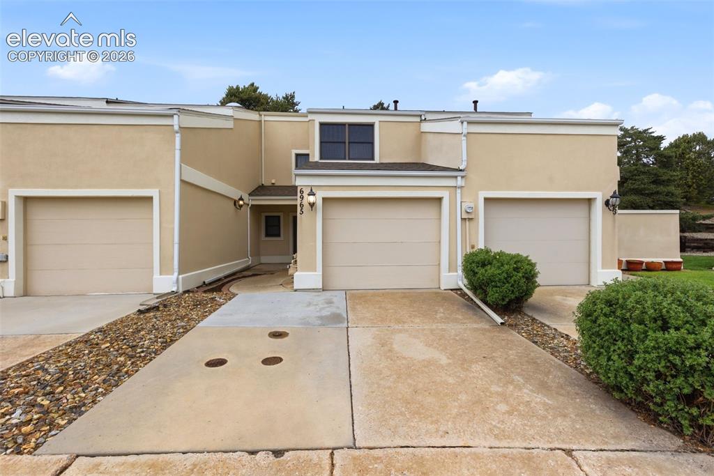 Image 2 of 50: Stucco exterior with multiple attached garages, concrete driveways, and a d