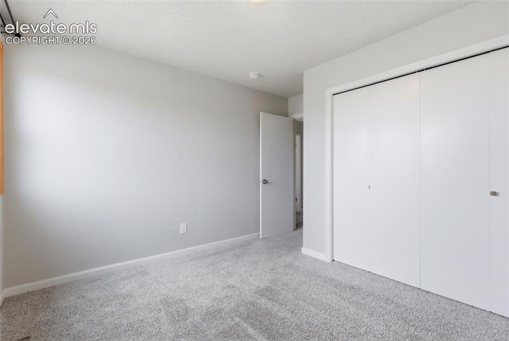 Image 21 of 50: Neutral-toned bedroom featuring wall-to-wall carpeting, light gray wall pai
