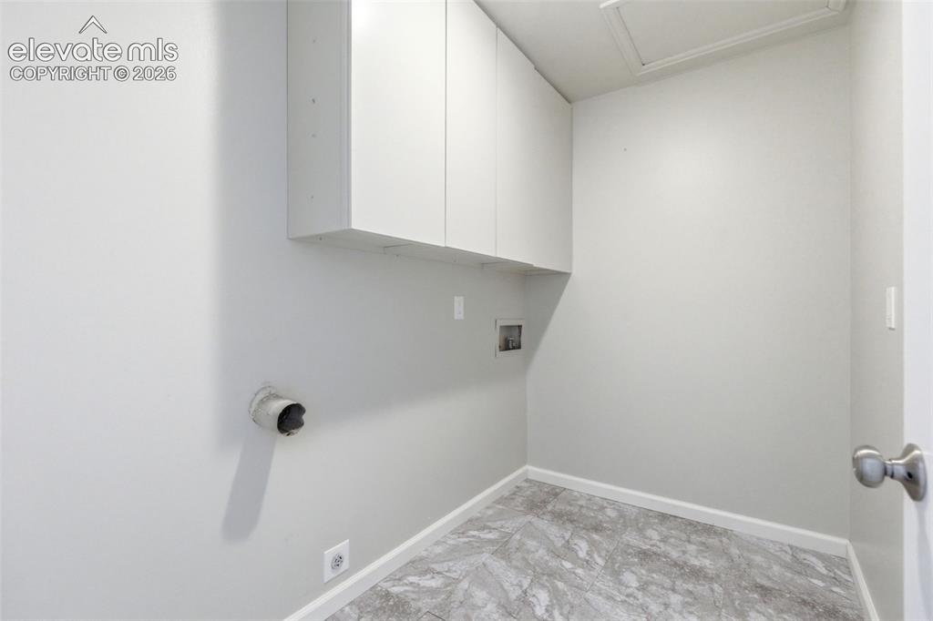 Image 22 of 50: Utility space featuring overhead cabinetry, light gray walls, and gray ston