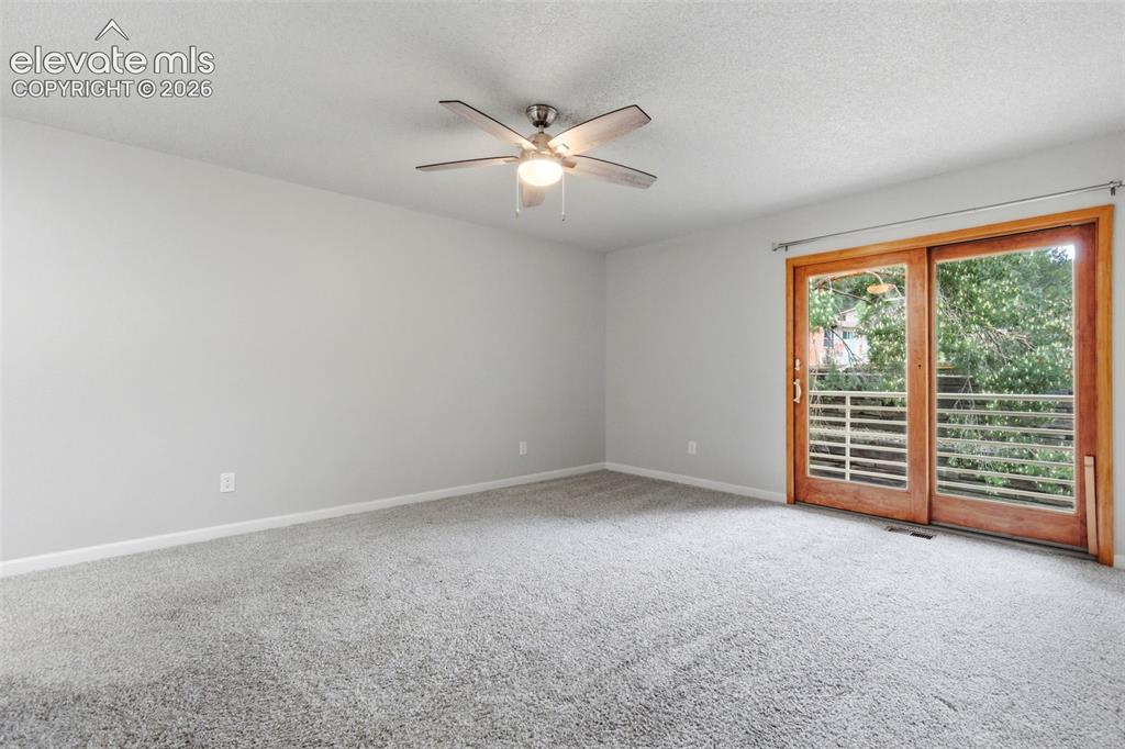 Image 23 of 50: Spacious primary suite featuring light gray walls, plush gray carpeting, an
