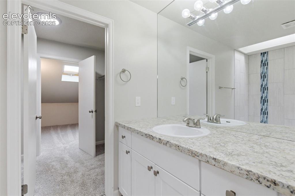 Image 29 of 50: Bathroom vanity featuring a speckled countertop, integrated sink, and white