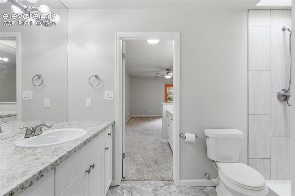 Image 31 of 50: Bathroom featuring a shower with tiled surround, a white toilet, and a vani