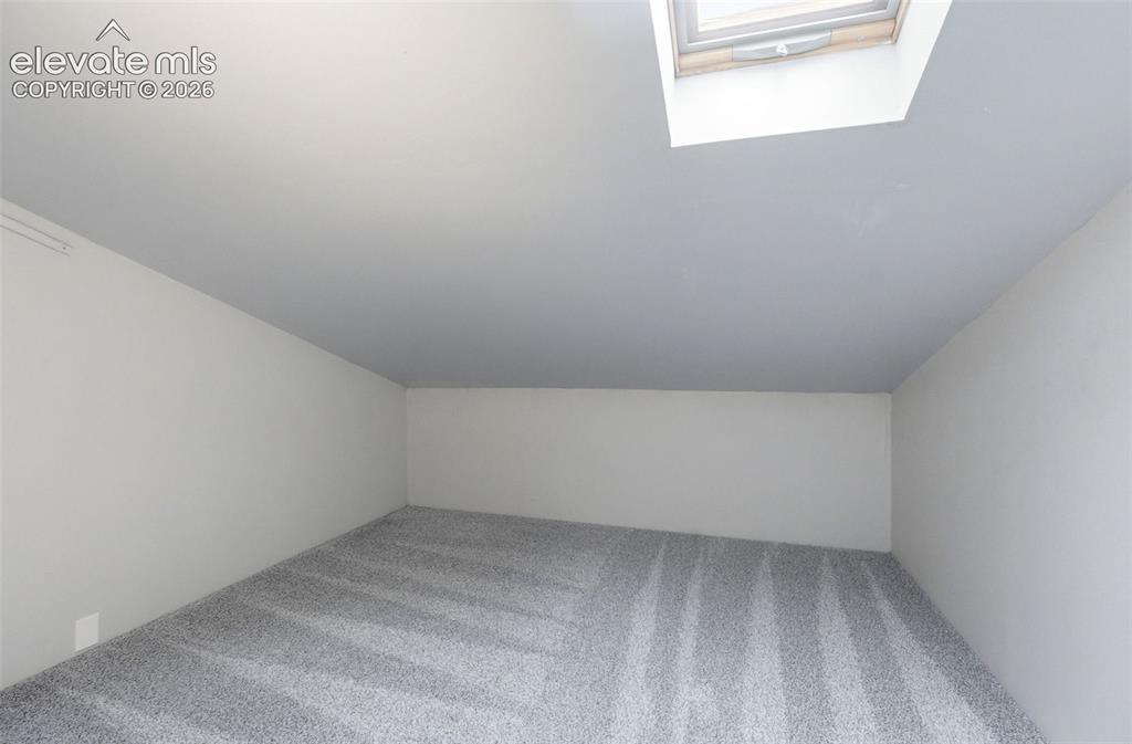 Image 33 of 50: Carpeted room featuring a skylight and sloped ceiling
