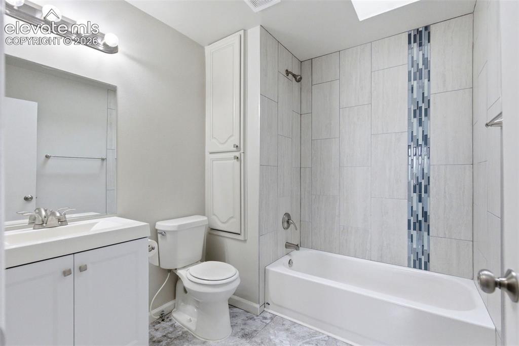 Image 35 of 50: Bathroom featuring a shower-tub combination with a decorative tile accent,