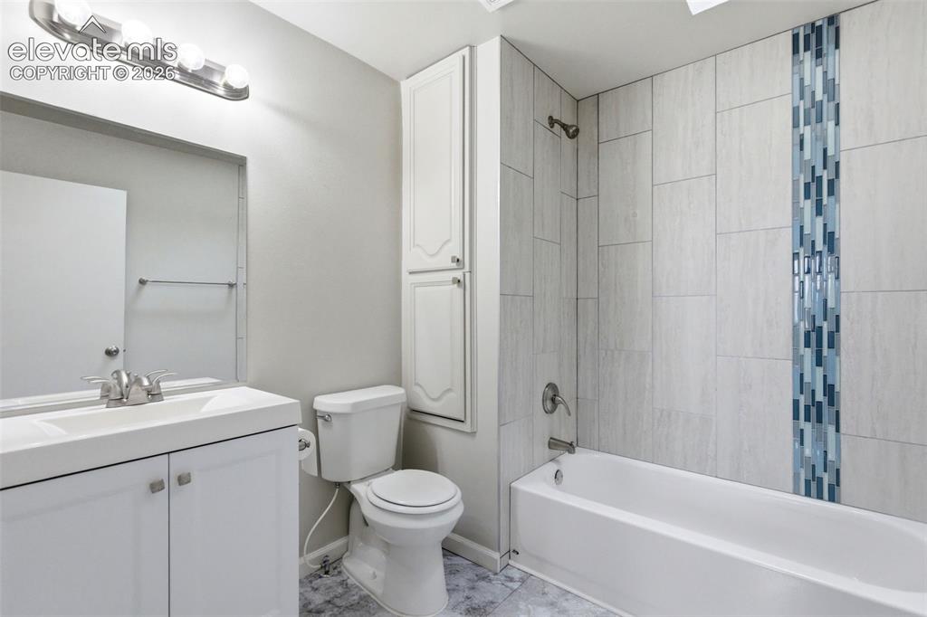 Image 36 of 50: Bathroom featuring a tiled tub shower with a decorative vertical tile accen