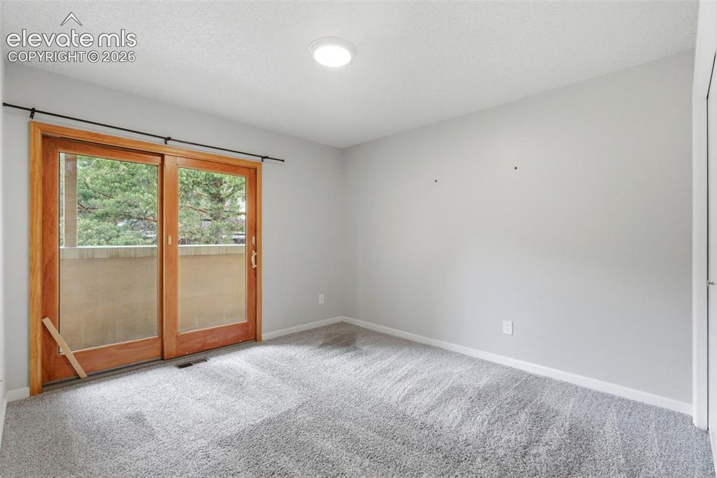 Image 37 of 50: Bedroom featuring light wood-frame sliding glass doors, a balcony with a st