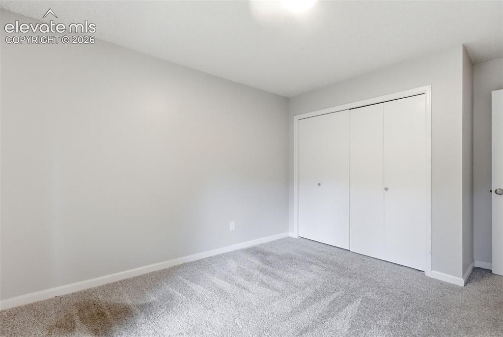 Image 39 of 50: Spacious room featuring light gray wall paint and a plush gray carpet