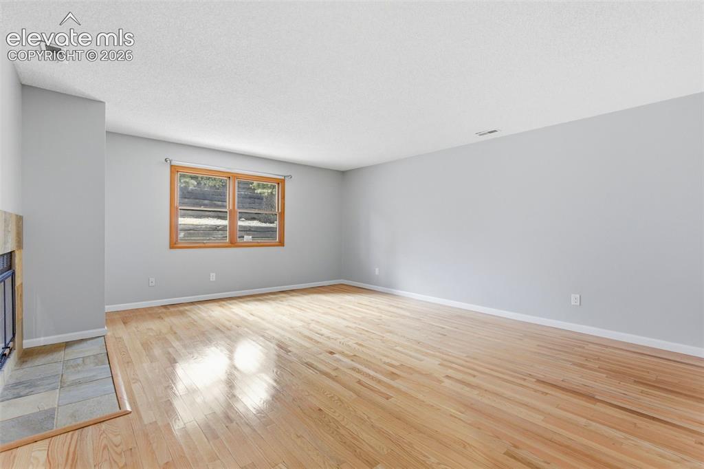 Image 4 of 50: Spacious interior featuring wood-finish flooring, light gray wall paint, an