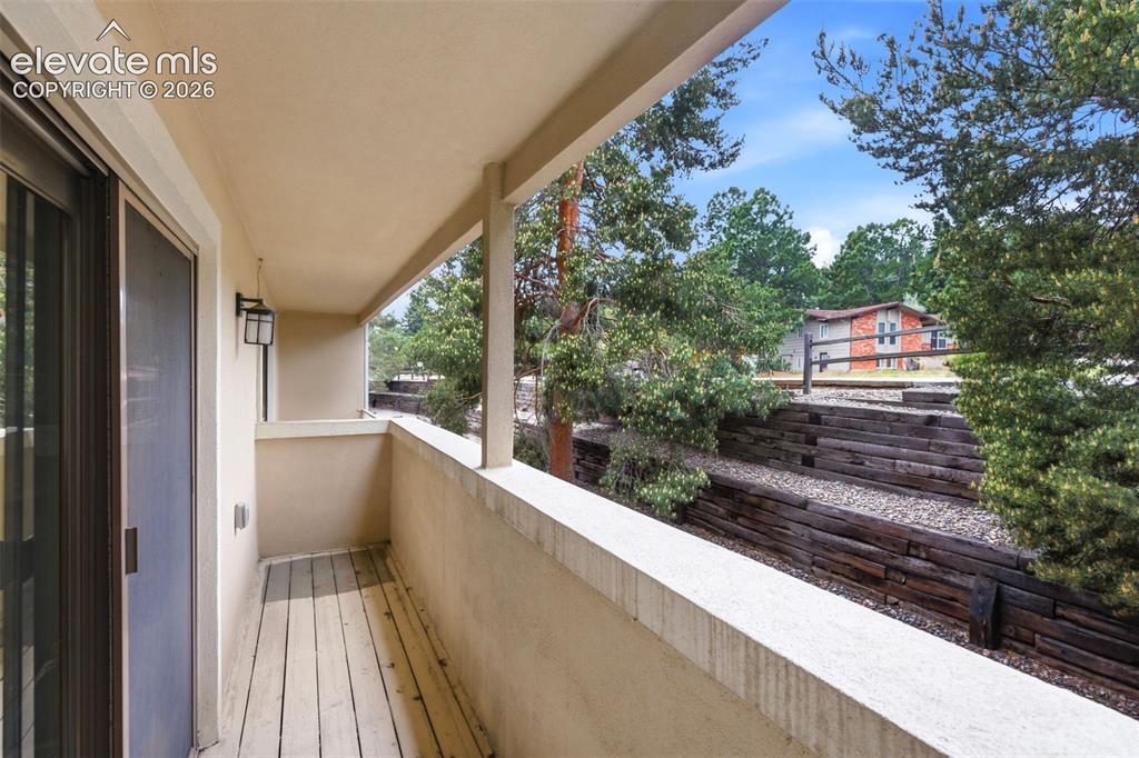 Image 42 of 50: Covered exterior balcony with sliding glass door access, plank flooring, an