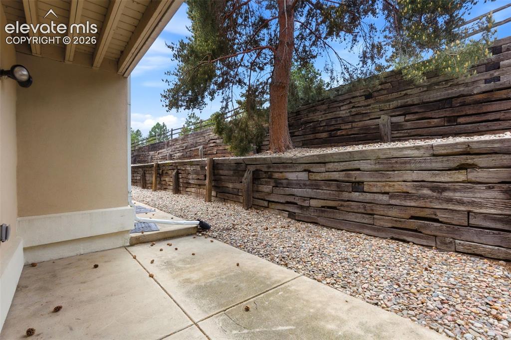 Image 43 of 50: Concrete patio with stucco exterior and exposed wood beam soffit