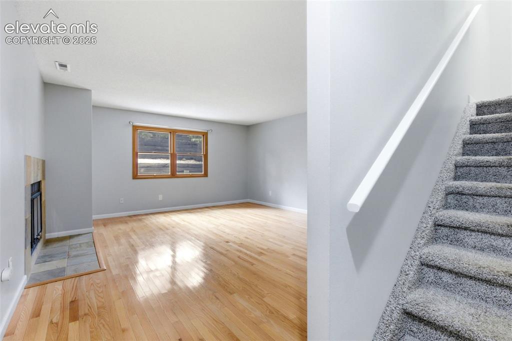 Image 5 of 50: Hardwood flooring extends throughout the living area, featuring a fireplace