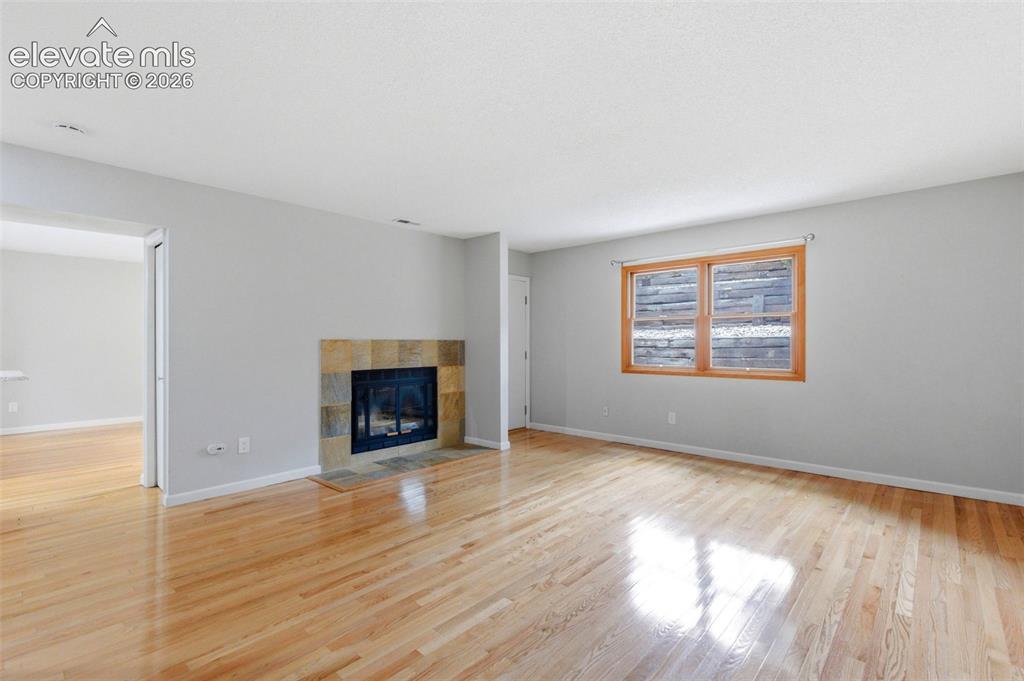 Image 8 of 50: Living area featuring light wood-finish flooring, a tile-surround fireplace
