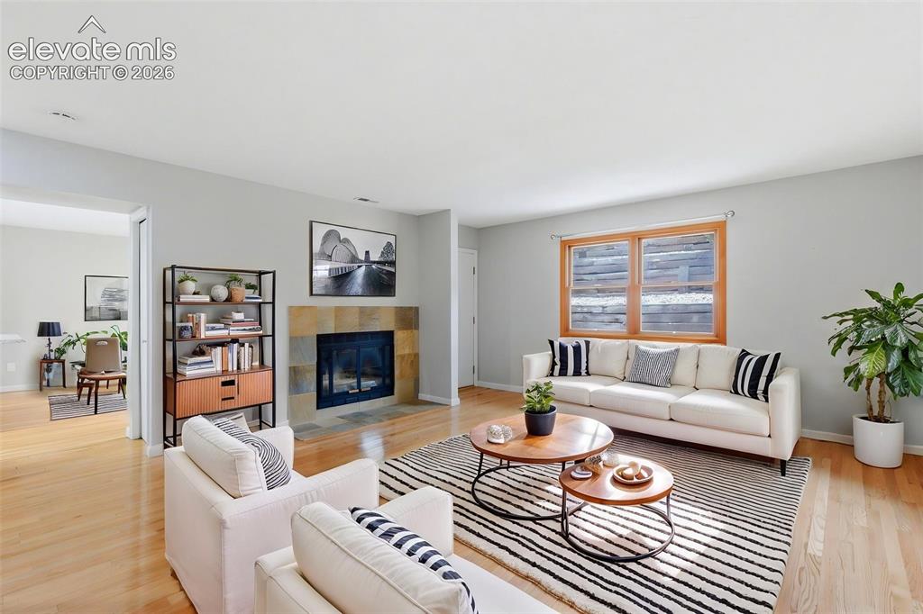 Image 9 of 50: Living area featuring wood-finish flooring, a stone-surround fireplace, and