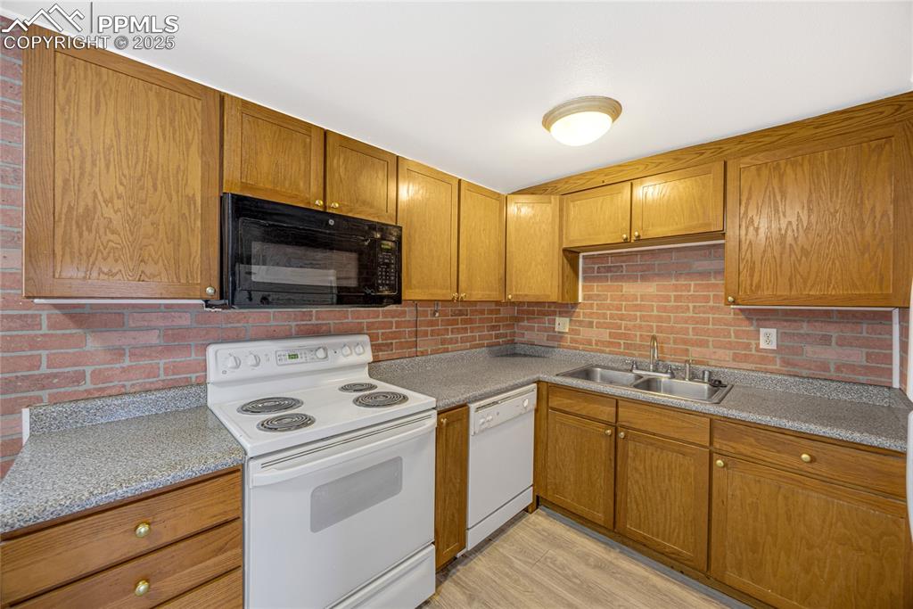 Image 10 of 24: Kitchen with white appliances, brown cabinetry, light wood-style floors, an