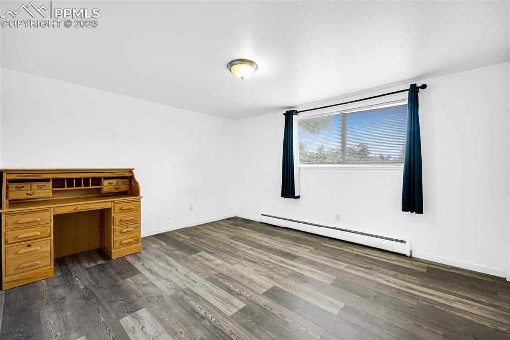Image 12 of 24: Unfurnished office with baseboard heating and dark wood-style floors