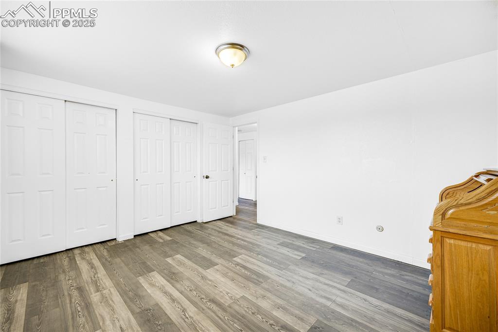 Image 14 of 24: Unfurnished bedroom with multiple closets and wood finished floors