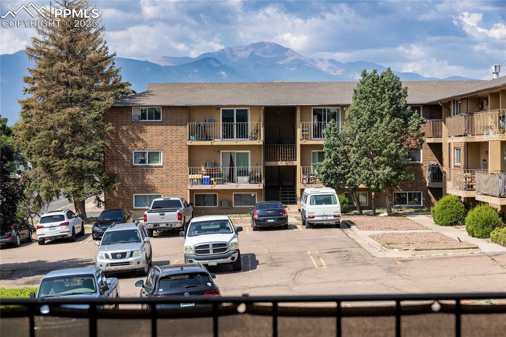 Image 21 of 24: View of building exterior featuring a mountain view and uncovered parking