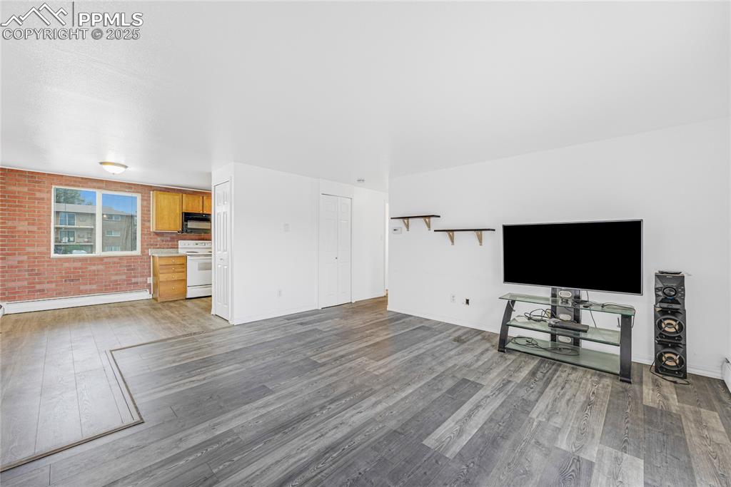 Image 5 of 24: Unfurnished living room featuring brick wall, light wood-style floors, and 