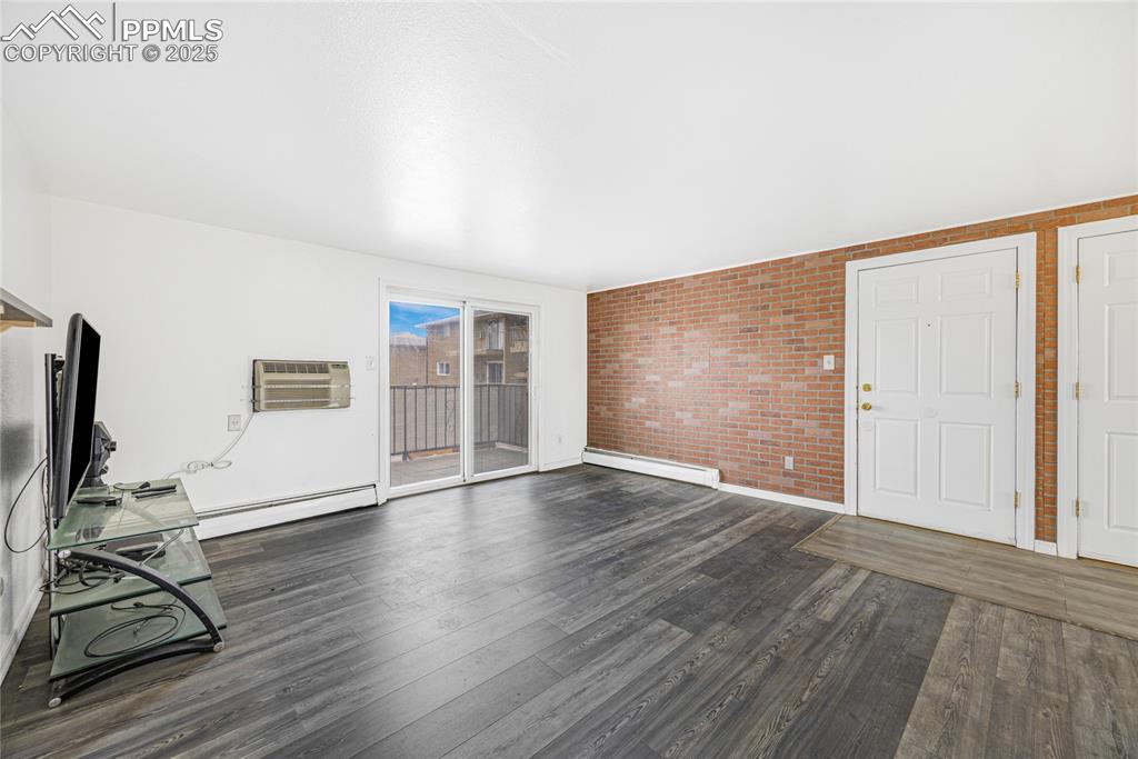 Image 7 of 24: Unfurnished living room featuring dark wood-style floors, baseboard heating