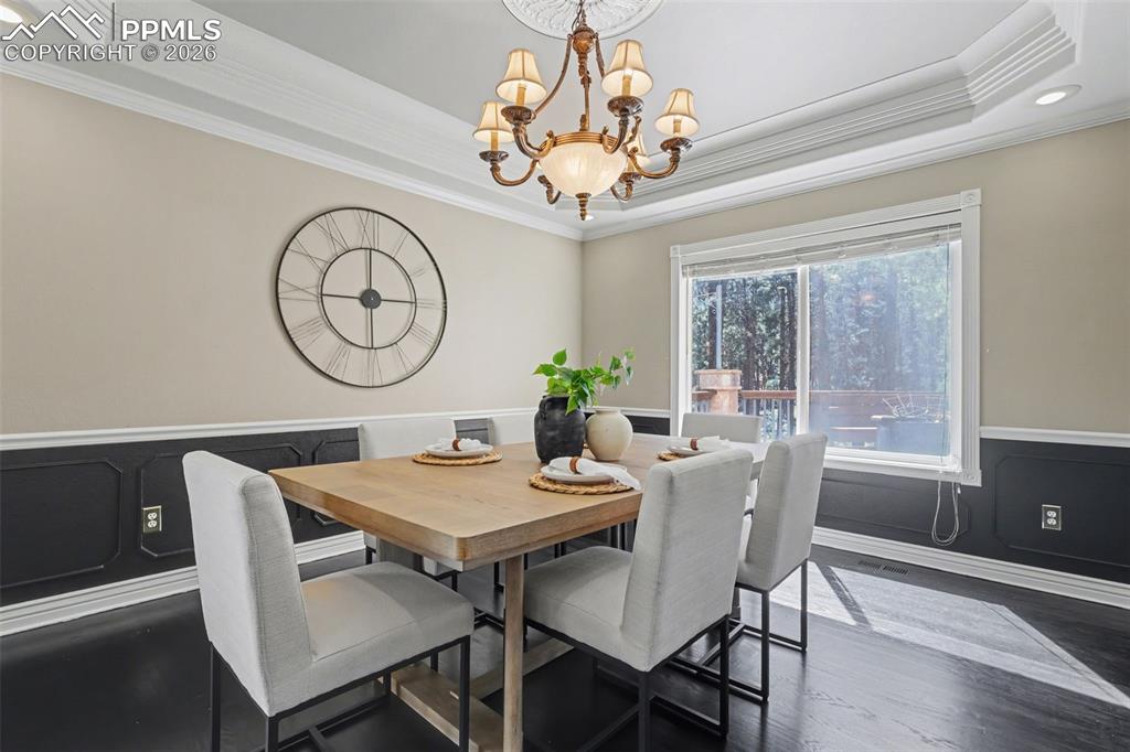 Image 10 of 44: Dining room featuring a wainscoted wall, ornamental molding, a chandelier, 
