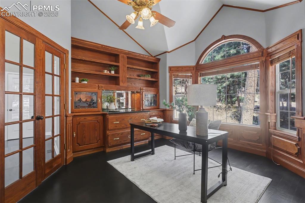 Image 13 of 44: Office space featuring vaulted ceiling, ceiling fan, french doors, and dark
