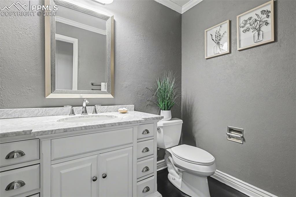 Image 14 of 44: Bathroom with a textured wall, ornamental molding, and vanity