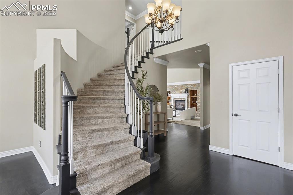 Image 15 of 44: Staircase featuring a high ceiling, crown molding, a fireplace, suspended l