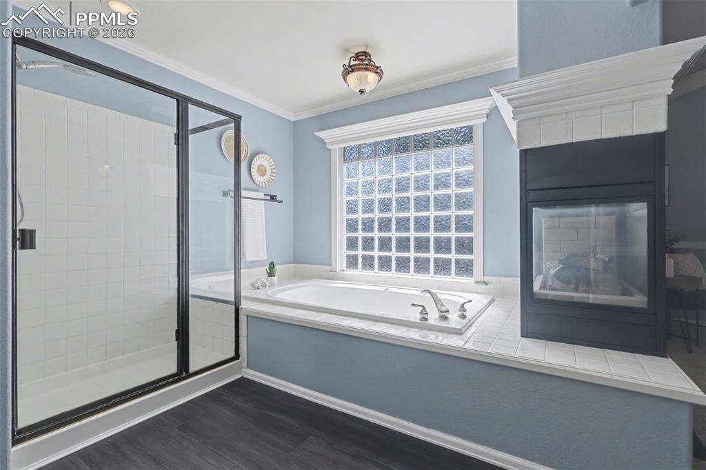 Image 20 of 44: Bathroom featuring a stall shower, a bath, dark wood-style floors, ornament