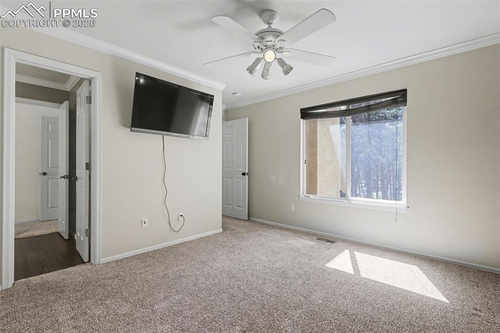 Image 24 of 44: Upstairs bedroom featuring crown molding, carpet flooring, a ceiling fan, w
