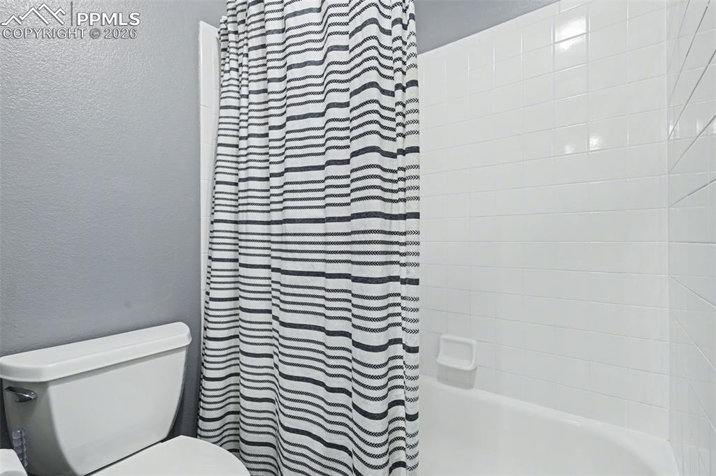 Image 27 of 44: Bathroom featuring a textured wall and shower / tub combo, shared access be