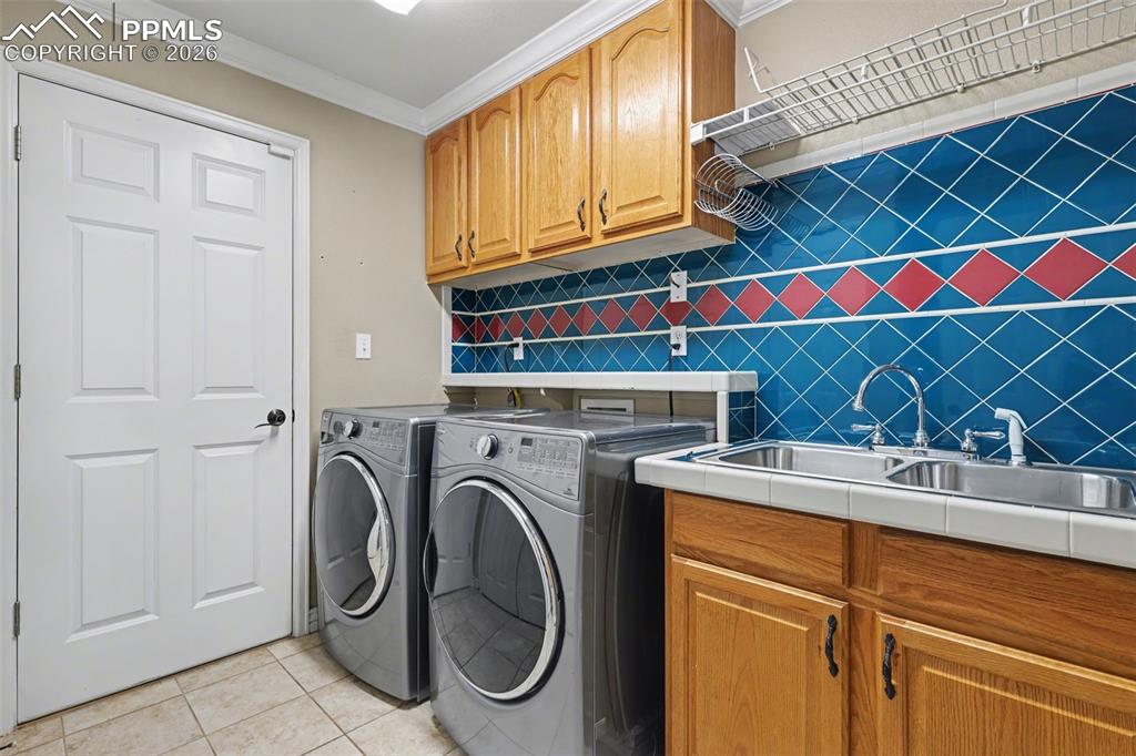 Image 28 of 44: main level Laundry room off garage featuring ornamental molding, separate w