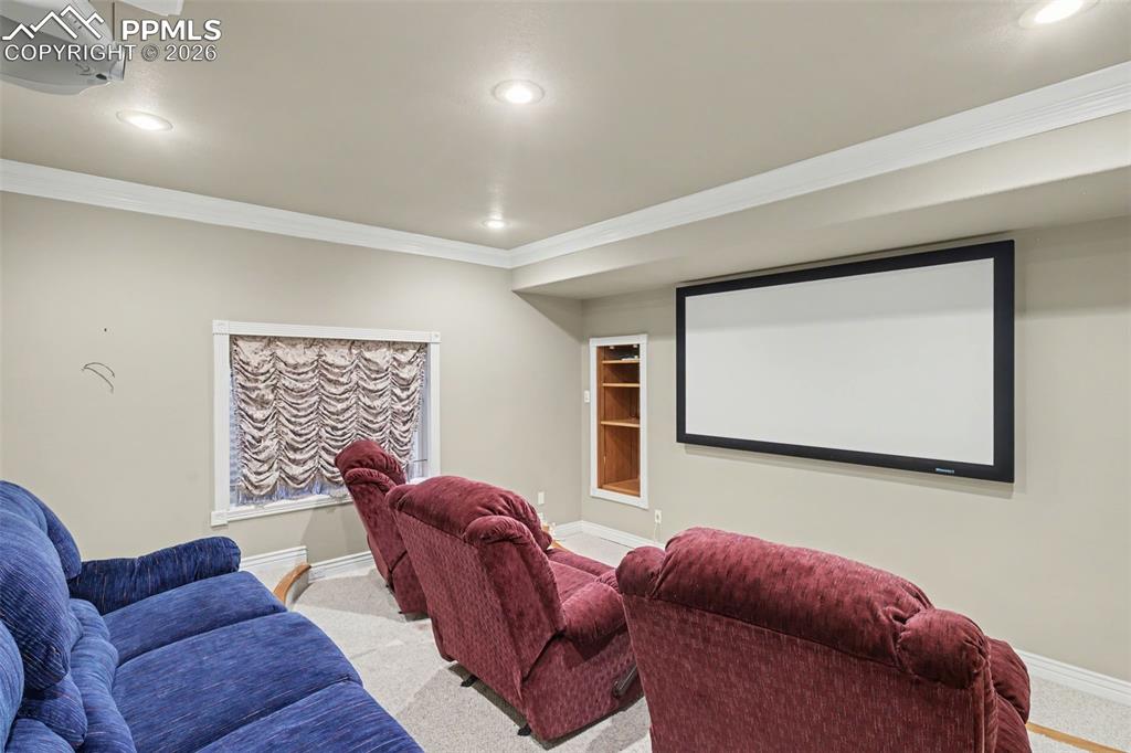 Image 33 of 44: Cinema room with crown molding, light carpet, recessed lighting, and built 