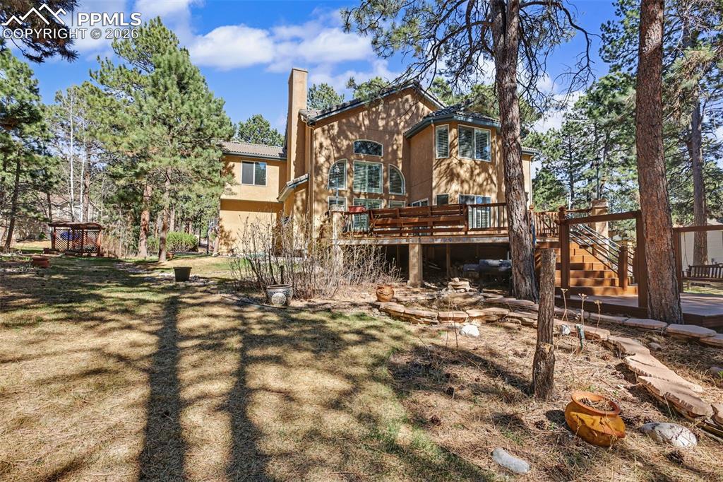 Image 38 of 44: Rear view of property with a wooden deck, a chimney, and stucco siding