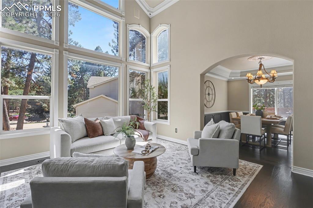 Image 5 of 44: Living area with ornamental molding, arched walkways, hanging lights, dark 