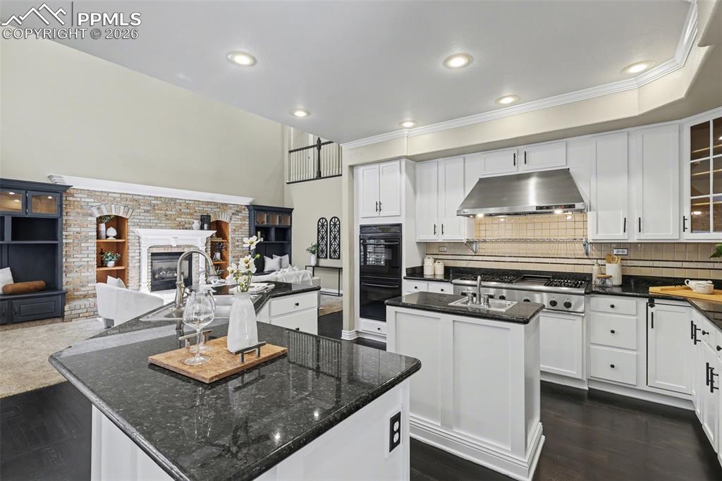 Image 6 of 44: Kitchen with open floor plan, white cabinets, dark wood-type flooring, rece