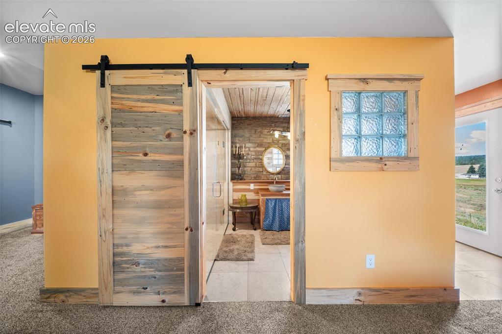 Image 18 of 41: Custom Bettkill pine barn doors lead to the private primary bath.