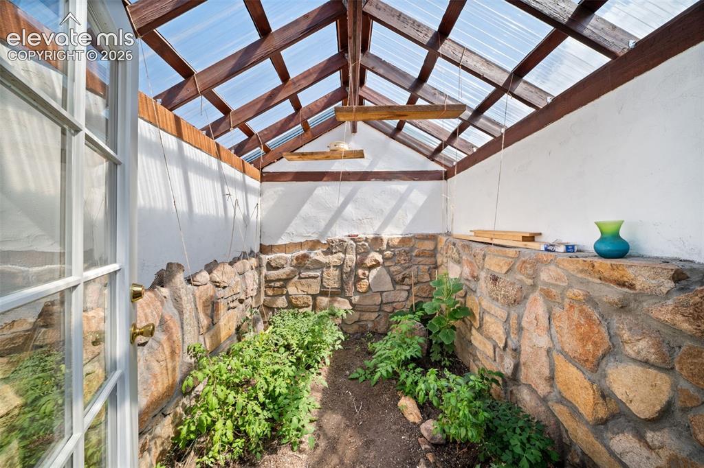 Image 31 of 41: Custom-built greenhouse with attractive stone accents.