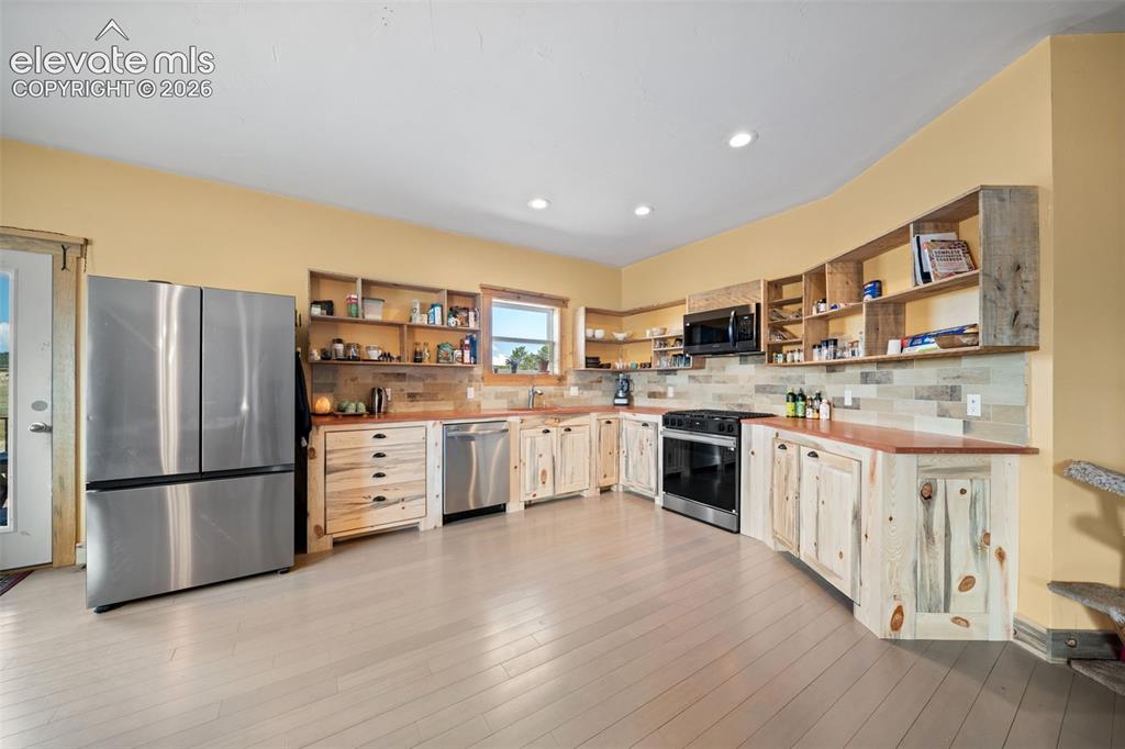 Image 9 of 41: Custom Bettkill pine cabinetry and fossil tile accents.
