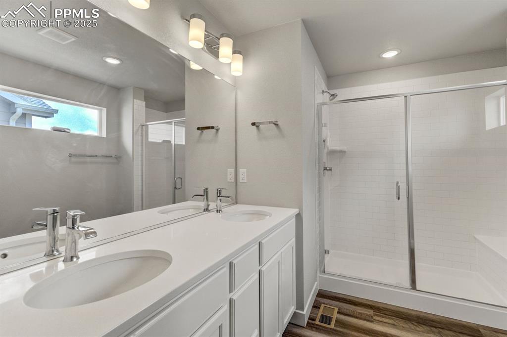 Image 25 of 50: Bathroom with a shower stall, visible vents, wood finished floors, and a si