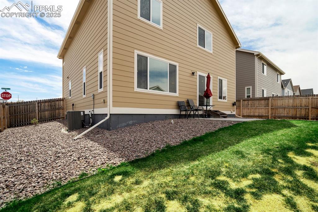Image 42 of 50: Rear view of property featuring a yard, a patio, central AC, and a fenced b