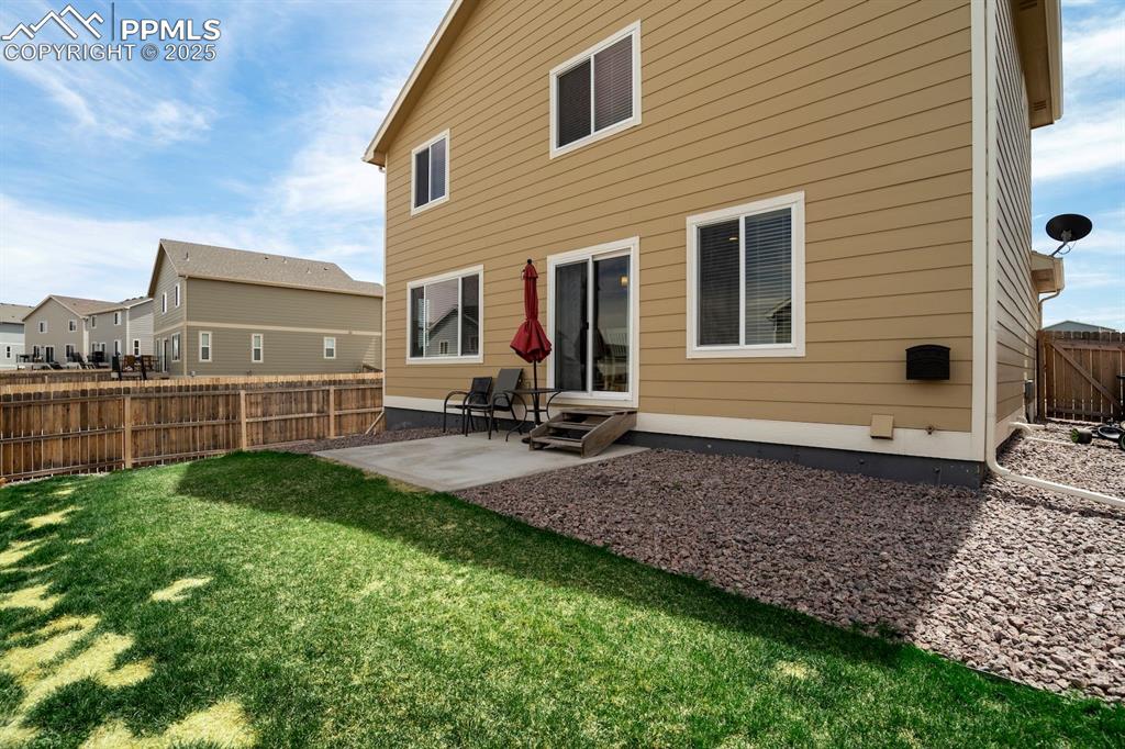 Image 43 of 50: Back of house featuring a fenced backyard, a patio area, a lawn, and entry 