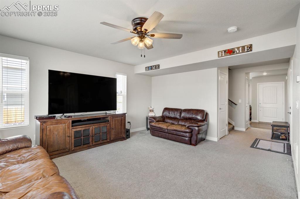 Image 9 of 50: Living area featuring baseboards, a ceiling fan, stairs, and light colored 