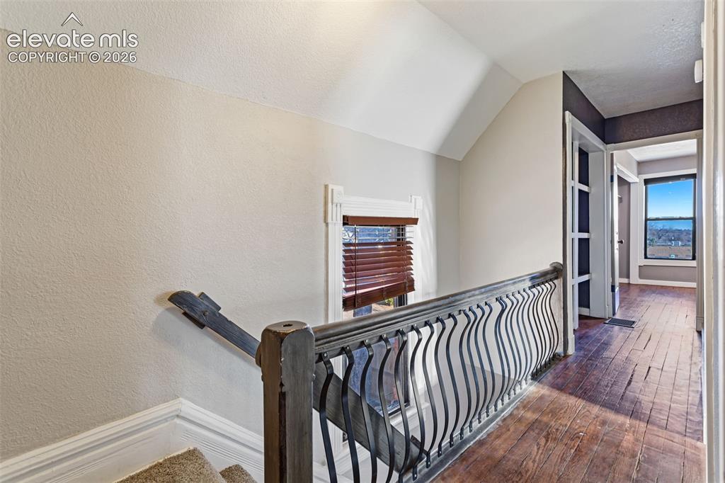 Image 15 of 35: Staircase with a dark wood-finish handrail and ornate black metal balusters