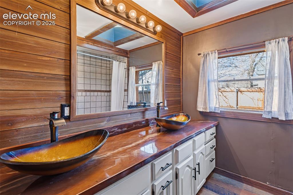 Image 17 of 35: Bathroom featuring a double vanity with vessel sinks, a spacious mirror, wo