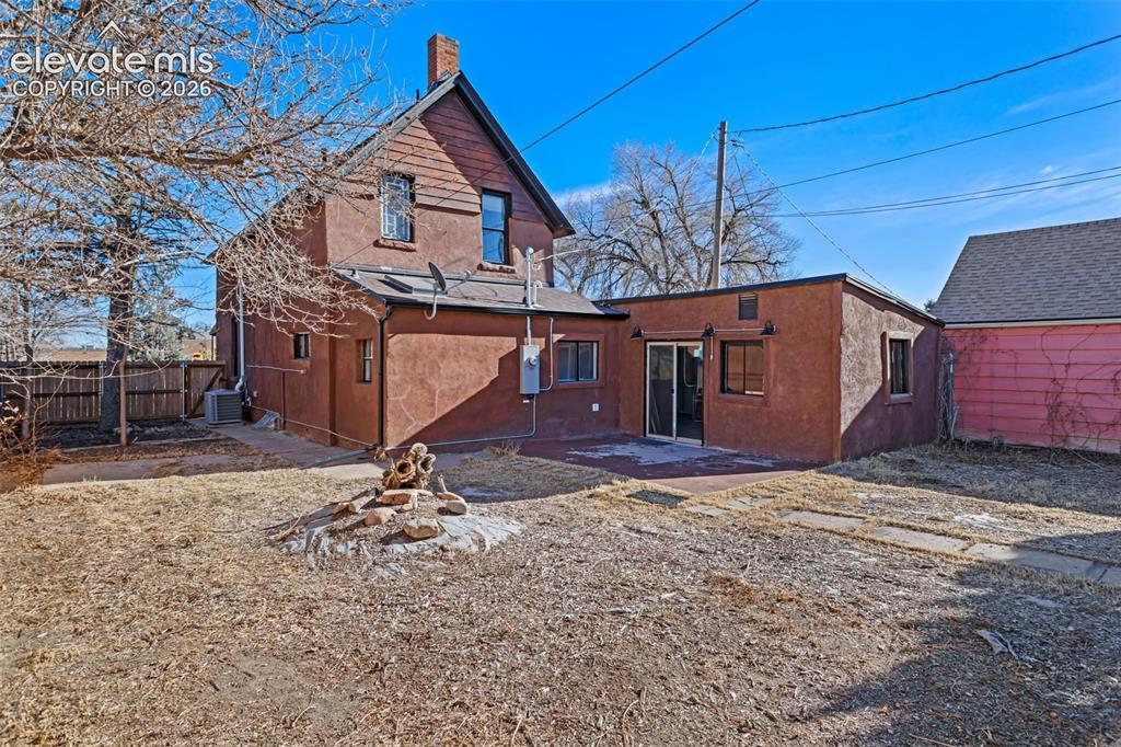 Image 27 of 35: Spacious backyard featuring an extended stucco addition, concrete patio, an
