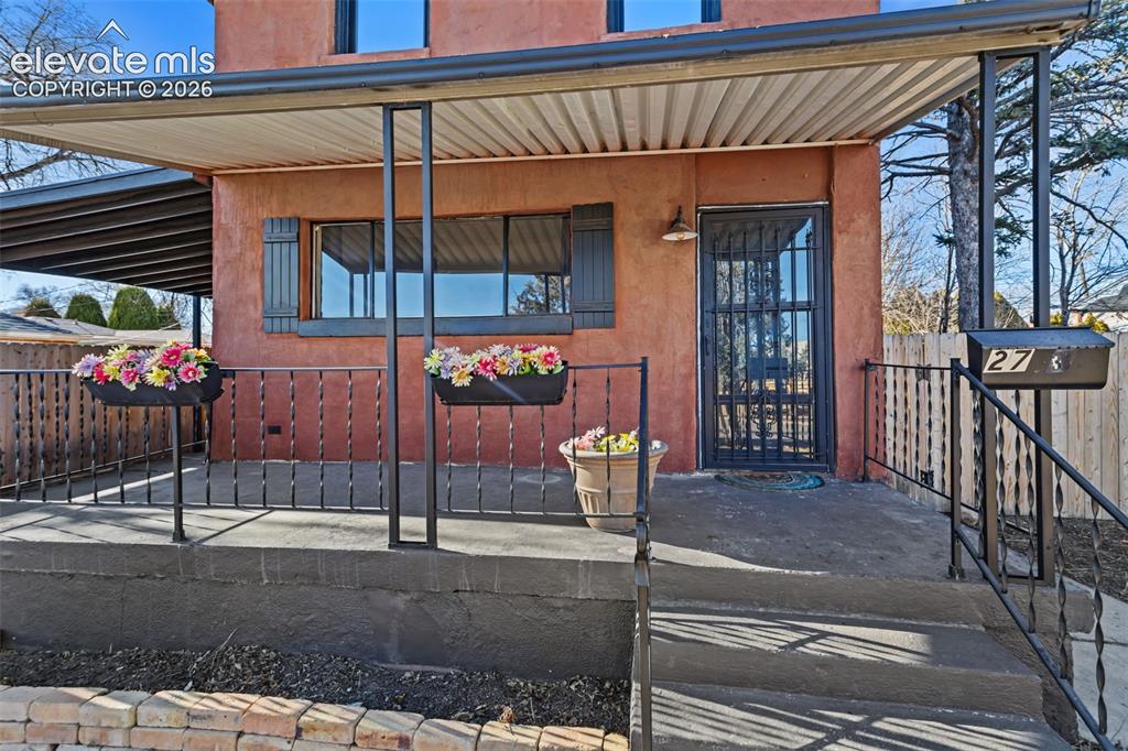 Image 3 of 35: Covered front porch with a concrete slab, wrought iron railings, and a secu