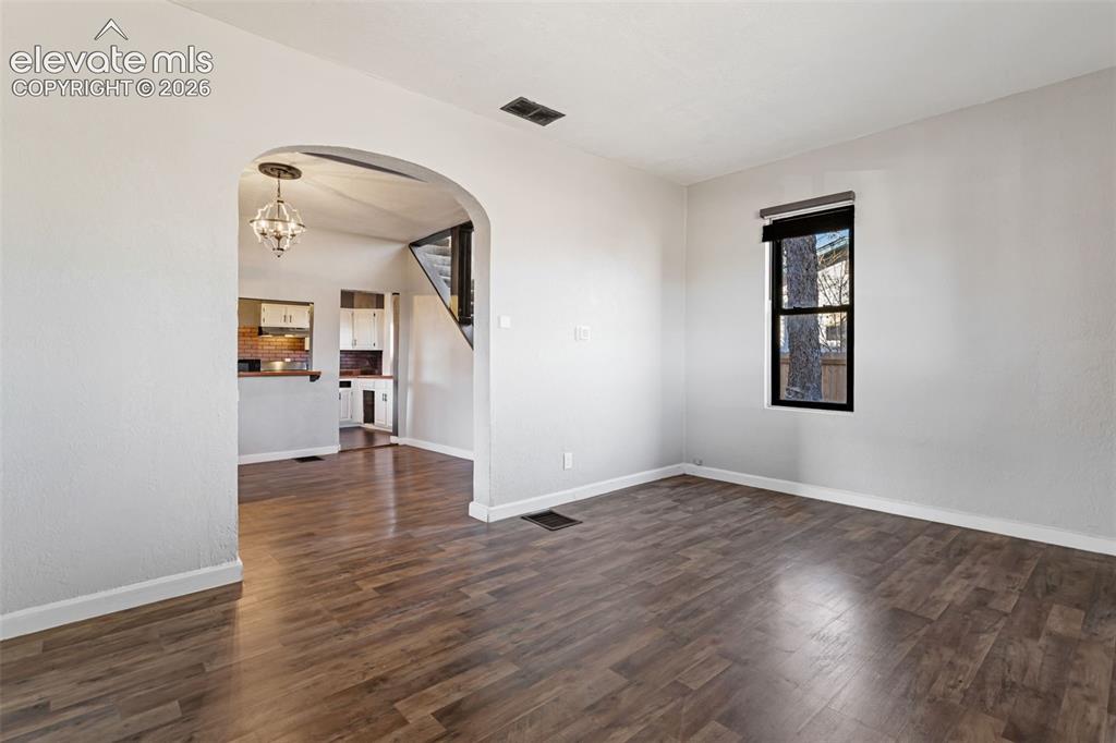 Image 5 of 35: Spacious interior featuring wood-finish flooring, an arched doorway, a clea