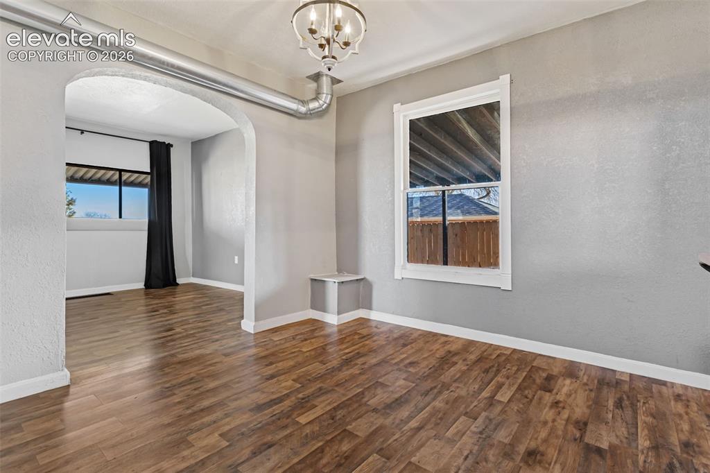 Image 7 of 35: Spacious interior featuring wood-finish flooring, a decorative chandelier,