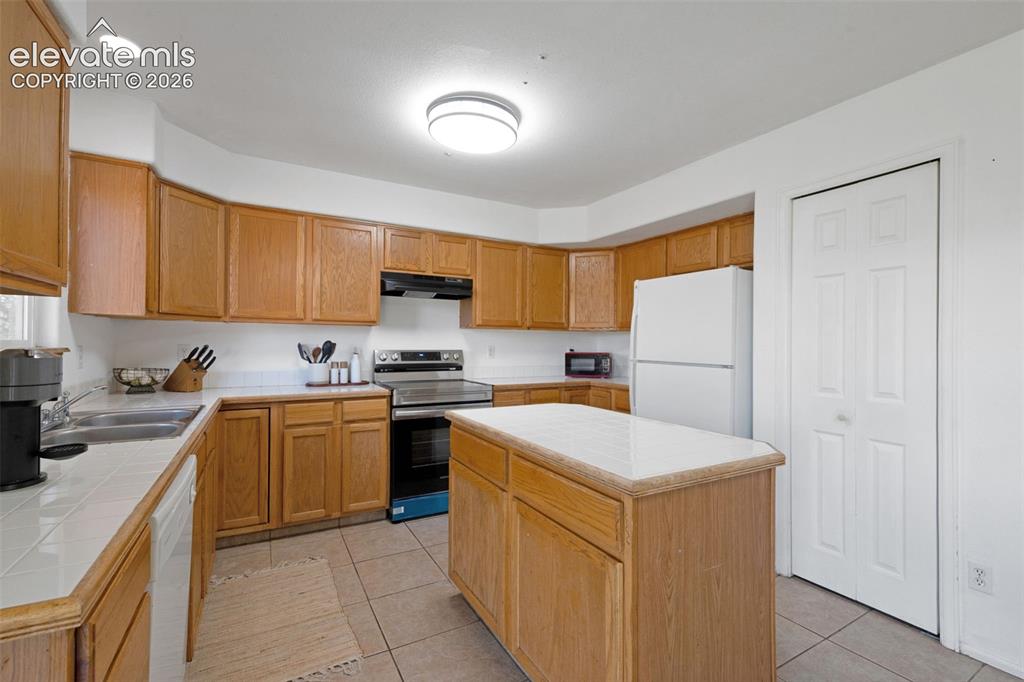 Image 10 of 31: Kitchen featuring light wood cabinetry, a central island with a solid surfa