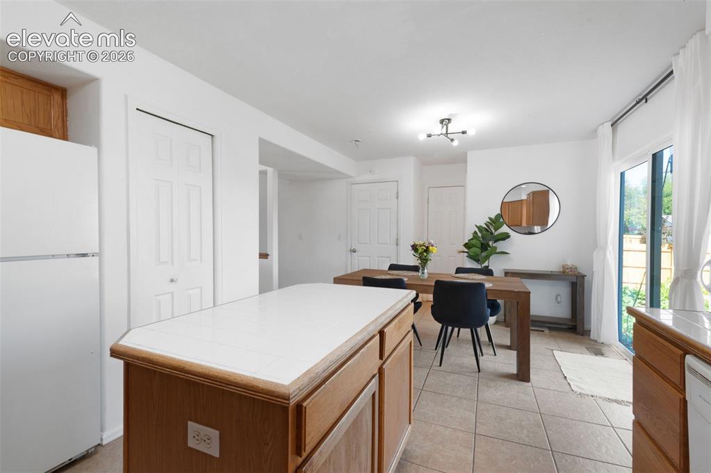 Image 11 of 31: Kitchen featuring wood-finish cabinetry, white tile countertops, and integr